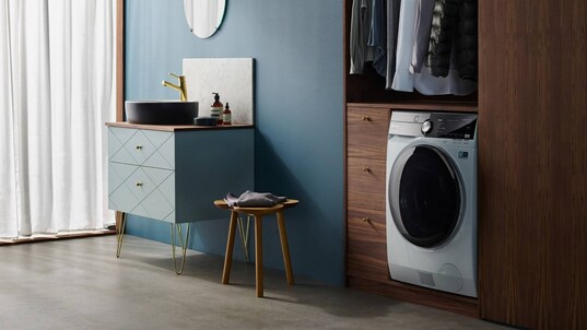 En kombinert vaskemaskin og tørketrommel fra Electrolux som står i et klesskap under et klesstativ. 
