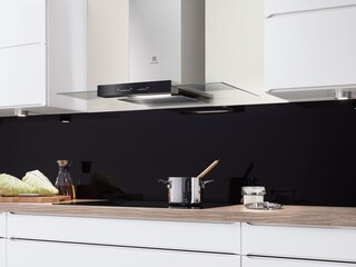 En fritthengende ventilator i glass og stål over et kokekar på en induksjonskoketopp