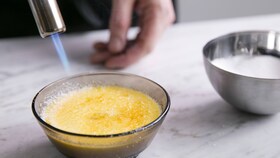 En baker karamelliserer sukkeret på en creme brulee med en blåselampe