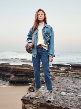 en kvinne står på en stein i en jeans jakke
