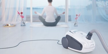 En kvinne gjør yoga med Electrolux Ultra Silencer-støvsugeren i forgrunnen