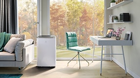 Air conditioner standing next to a sofa and a desk