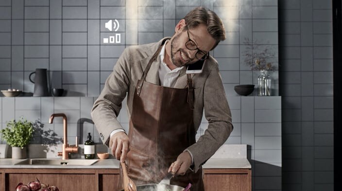 man snakker i mobil når han lager mat