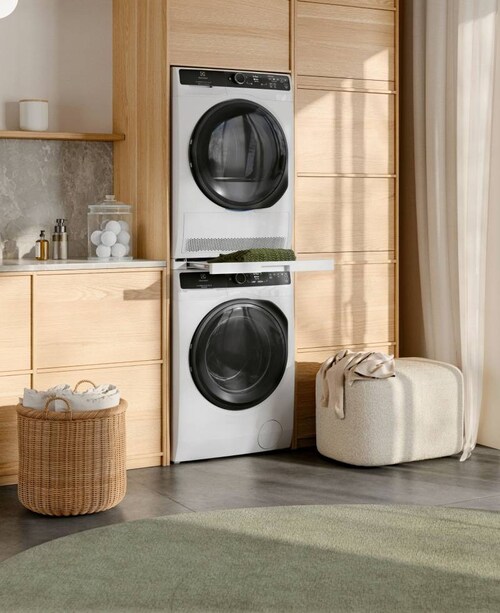 Electrolux vaskemaskin og tørketrommel som er stablet oppå hverandre i et rom opplyst av solskinn.