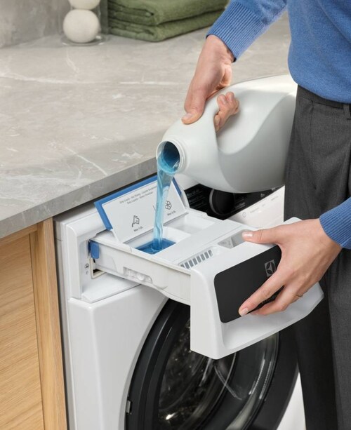 En person heller vaskemiddel i en Electrolux vaskemaskin.