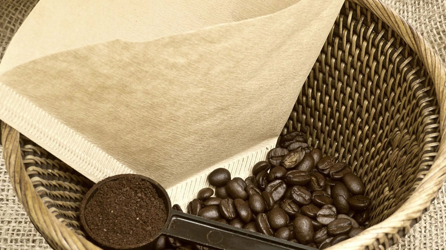 Kaffebønner, kaffefilter og måleskje.