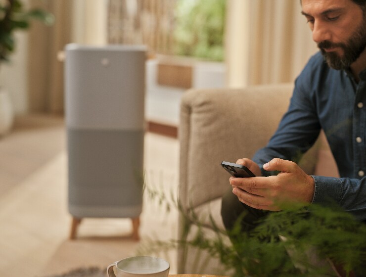 Mann som holder telefonen sittende ved siden av luftrenser