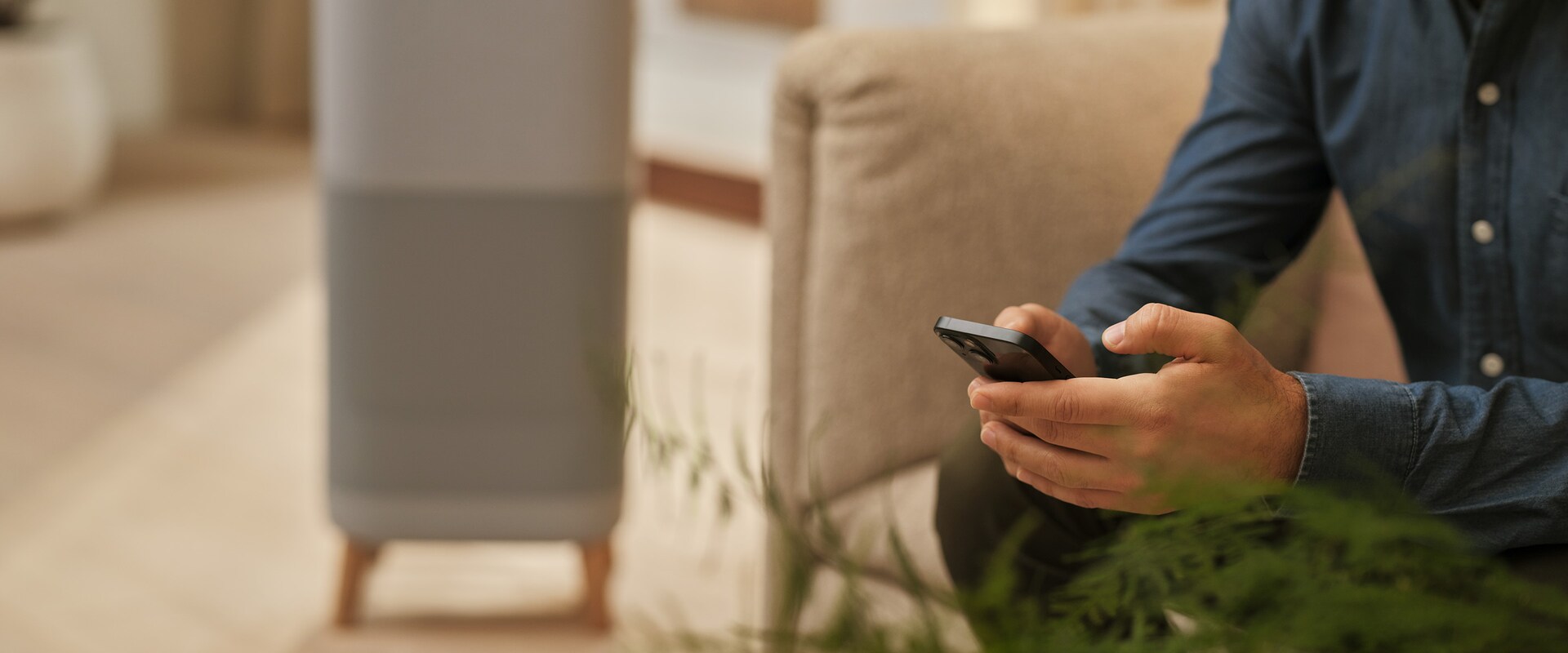 Hånd som holder telefon med luftrenser i bakgrunnen