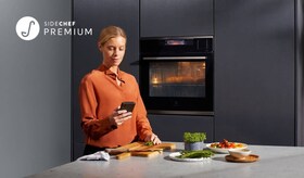 en kvinne i et kjøkken med sidechef appen i hånden