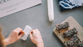 Hender som knyter en rosett på mat