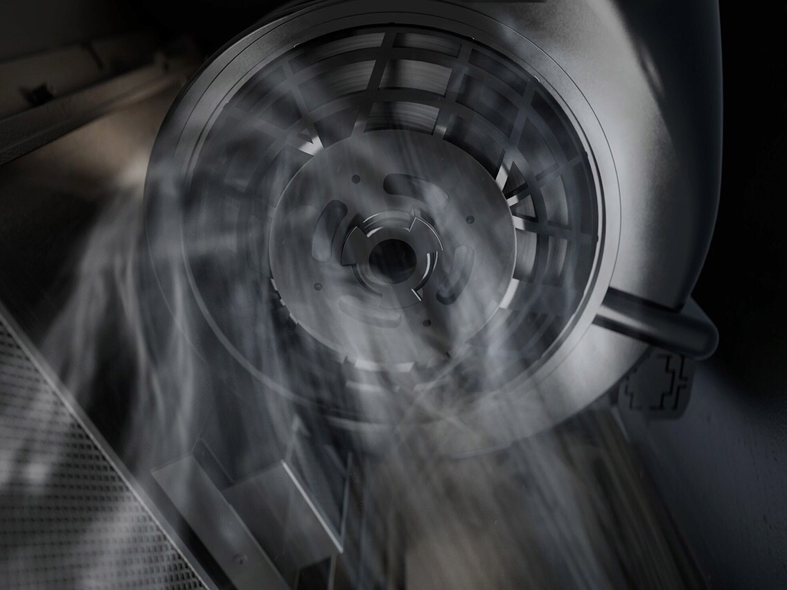 Nærbilde innenfra en kjøkkenventilator som viser viftemotoren og filtersystemet som suger opp matos og damp.
