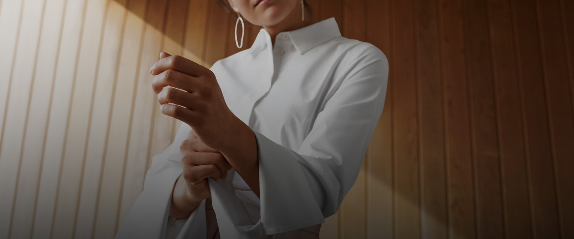 En kvinne bretter opp armen på sin hvite skjorte