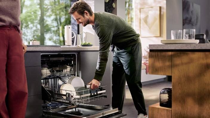 En mann tømmer oppvaskmaskinen.
