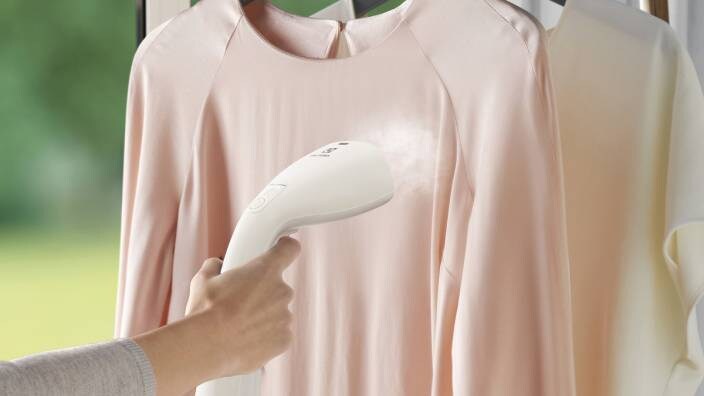 En rosa genser steames med en klesdamper.