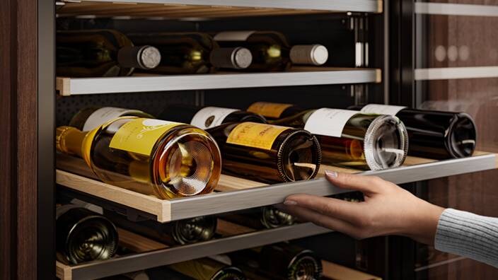 Nærbilde av vinflasker i et vinskap.